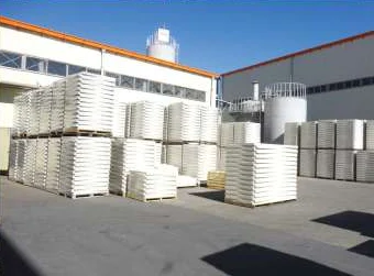 Stacked white GRP panels stored outdoors at the factory